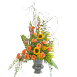 Tall bouquet of orange roses and sunflowers in a gray vase