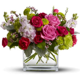 Pink and red roses in a clear glass vase with green and white accents