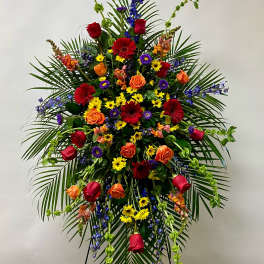 Large standing floral spray with roses, daisies, and palm fronds