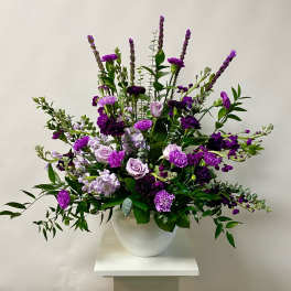Purple floral arrangement in a white vase