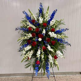 Standing floral spray with red roses, white blooms, and blue flowers