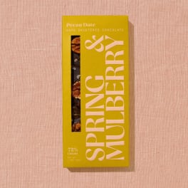 Box of pecan date chocolate on a pink textured surface