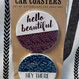 Packaged set of two round car coasters with printed text and patterns
