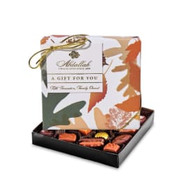 Box of assorted chocolates with a patterned gift lid and gold ribbon