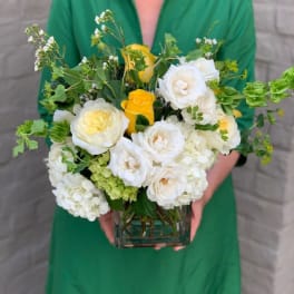 White and yellow flower arrangement in a square glass vase