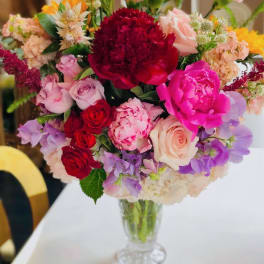 Mixed bouquet of pink, red, and purple flowers in a clear glass vase