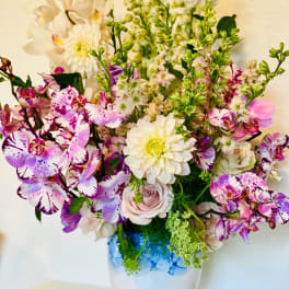 Mixed pink, white, and purple flowers in a white vase
