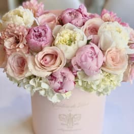 Pink and white bouquet of peonies and roses in a pale pink box
