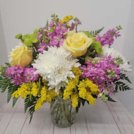 Bouquet of yellow roses, white chrysanthemums, and pink flowers in a glass vase