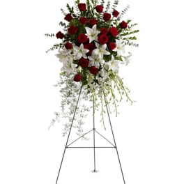 Standing floral spray with red roses and white lilies on an easel