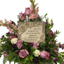 Pink and white roses surround a memorial plaque with a heaven message.