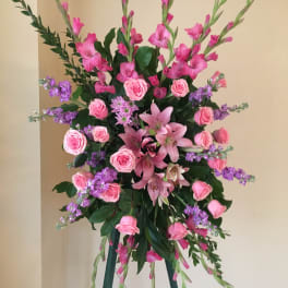 Standing floral spray with pink roses, lilies, and purple accents