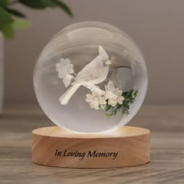 Glass orb with a white bird and flowers on a wooden base