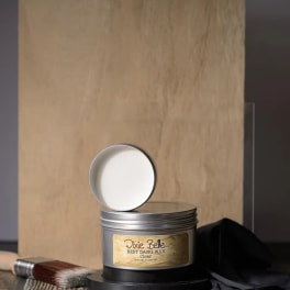 Tin of clear wax with a brush beside it