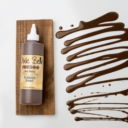 Bottle of brown gel stain on a wooden board with stain swatches beside it