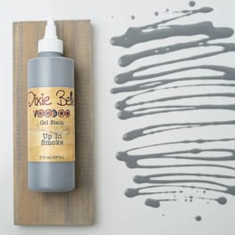 Bottle of gray gel stain on a wood board beside gray paint swatches
