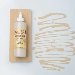 Bottle of Dixie Belle Voodoo Gel Stain on a wood board with beige stain swatches
