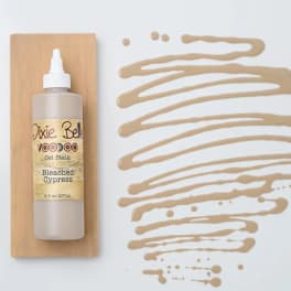 Bottle of gel stain on a wood board beside tan paint swatches