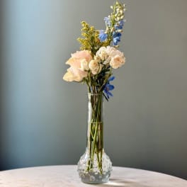 Mixed pastel flowers in a clear glass vase on a table
