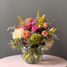 Mixed bouquet in a clear glass vase with pink, peach, white, and yellow blooms
