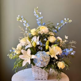 Blue and white floral arrangement in a woven basket on a round table