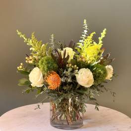 White roses and orange pincushion flowers in a clear glass vase