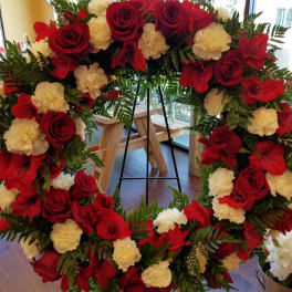 Large red and white floral wreath on a black stand