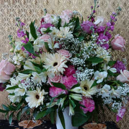 Large mixed bouquet of pink, white, and purple flowers in a white vase