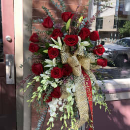 Tall standing arrangement of red roses and white lilies with a gold ribbon