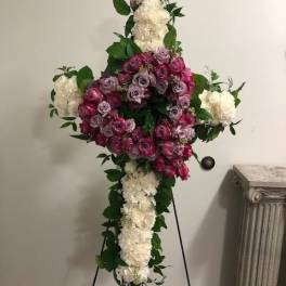 Standing floral cross with pink roses and white flowers on an easel