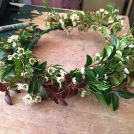Floral crown with small white blossoms and mixed greenery on a table