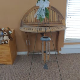 Greenery tied with a white bow on a metal wind chime stand