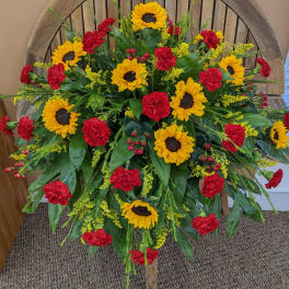 Large standing floral spray with sunflowers and red carnations