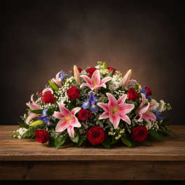 Low floral arrangement with pink lilies, red roses, and blue irises