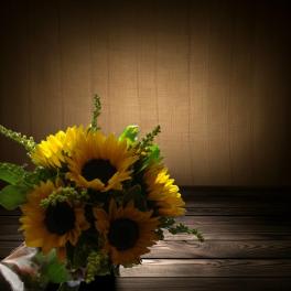 Bouquet of sunflowers with green filler on a wooden surface