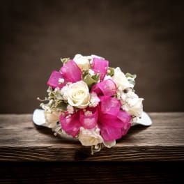 White rose bouquet with bright pink ribbon on a table