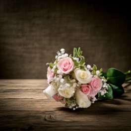 Small bouquet of pink and white roses on a wooden surface