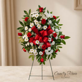 Standing floral wreath with red roses, white daisies, and a red ribbon bow