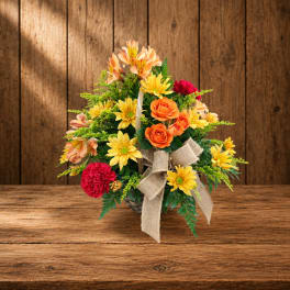 Mixed flower arrangement in a basket with a burlap bow