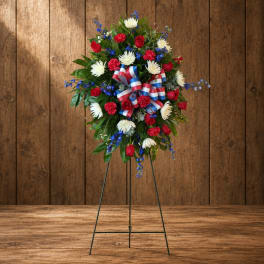 Standing floral wreath with red, white, and blue flowers on an easel