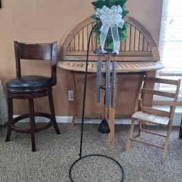 Wind chime with a white bow hanging on a black stand
