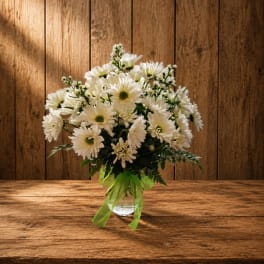White daisy bouquet in a clear glass vase with a green ribbon