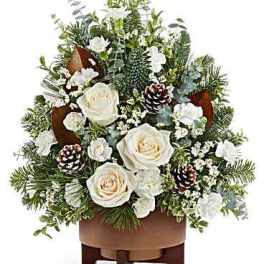 White roses and pinecones in a brown container with evergreen accents