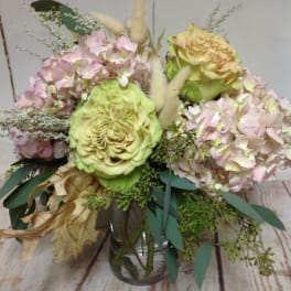 Pastel arrangement of green roses and pink hydrangeas in a clear glass vase