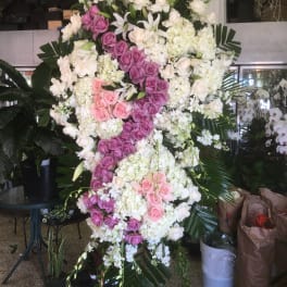 Large standing floral spray with pink, purple, and white roses