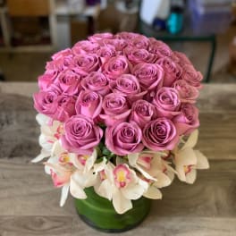 Pink rose bouquet with white orchids in a green vase