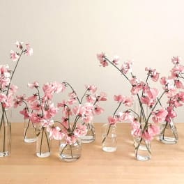 Pink flowers in small glass vases on a wooden table