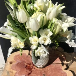 White tulips and lilies arranged in a textured white vase