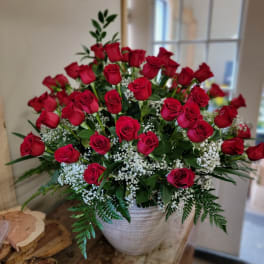 Red roses arranged in a white vase with baby's breath