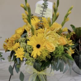 Yellow bouquet in a glass vase with gerbera daisies and roses